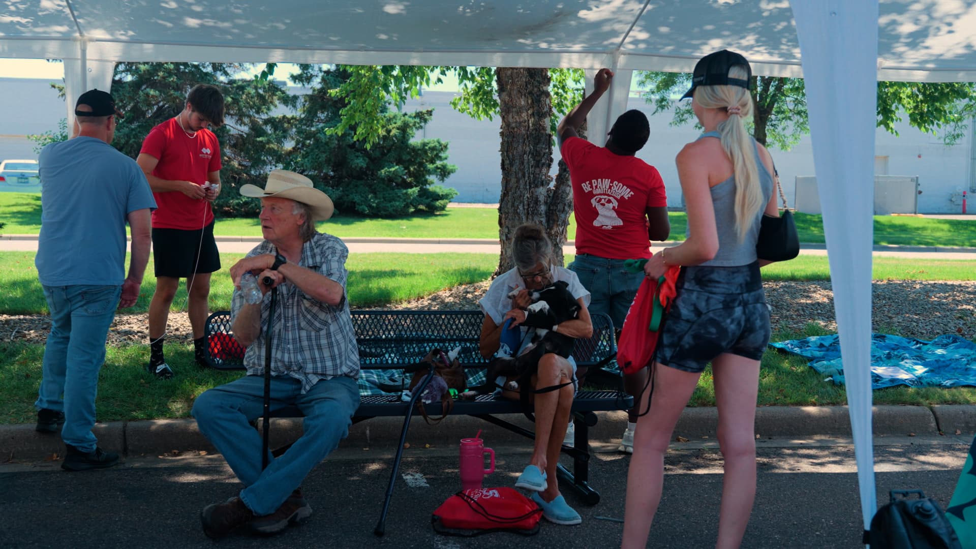 Attendees and adoptable dogs gathered under a canopy at a community adoption event